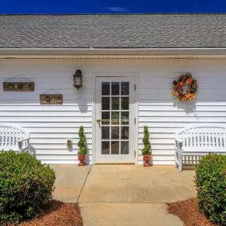 Front view of a house entrance with white siding, decorated with a wreath and flanked by benches.