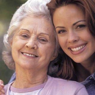 A grandmother and granddaughter smiling together outdoors.