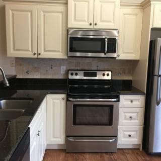 A modern kitchen featuring stainless steel appliances and cream-colored cabinets.