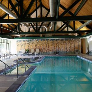 An indoor swimming pool with a wooden ceiling and lounging chairs.