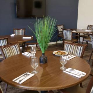 A neatly set dining table with glassware and napkins in a restaurant's interior.