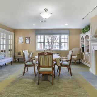 A cozy living room with a table and chairs near a window.