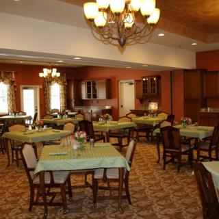 A warmly lit dining area with multiple tables and classic chandeliers.