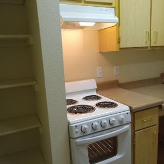 A cozy kitchen featuring a white stove and yellow cabinetry.