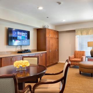 A cozy living room with a TV, wooden cabinets, and comfortable seating.