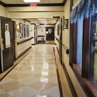 A well-lit, decorated hallway featuring framed photographs along the walls, typical of a healthcare or institutional setting.