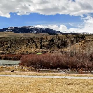 Scenic view of a river flowing through a mountainous landscape with clouds in the sky.