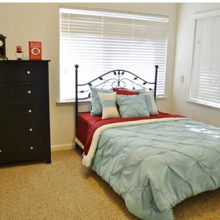 A cozy bedroom with a neatly made bed and a dresser.