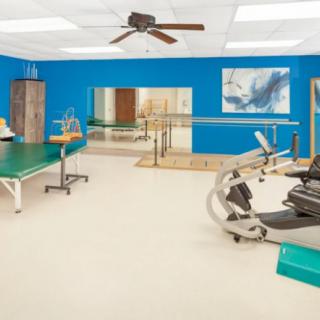 A well-equipped rehabilitation center with exercise equipment and therapy tables.