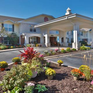 Image of a well-landscaped building entrance with colorful flowers and clear blue sky.