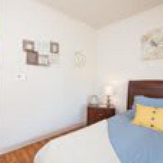 A cozy bedroom with a neatly made bed, bedside table, and wall decorations.