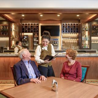 A waitress taking an order from a couple seated at a restaurant table.