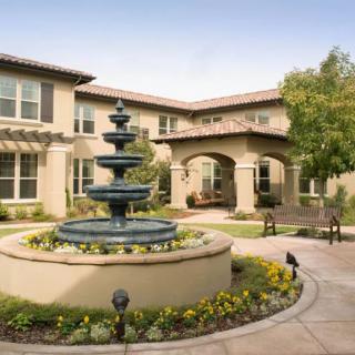 A beautifully landscaped courtyard with a central fountain surrounded by a building.
