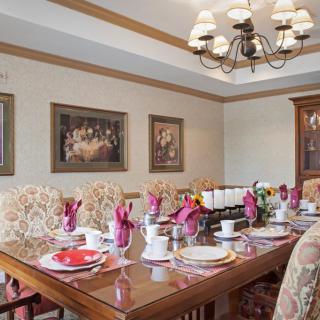 A beautifully set dining room table with elegant decor and a chandelier overhead.