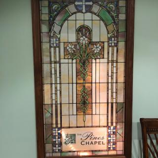A beautifully crafted stained glass window featuring a cross, located in a chapel.
