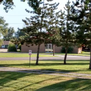 A serene view of a grassy area with trees and a building in the background.
