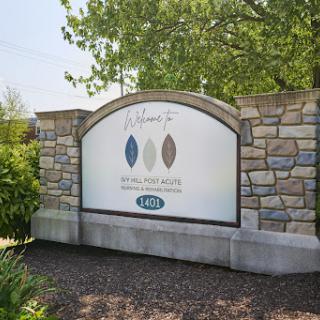 A well-designed stone sign displaying colors and branding elements, set in a lush outdoor environment.