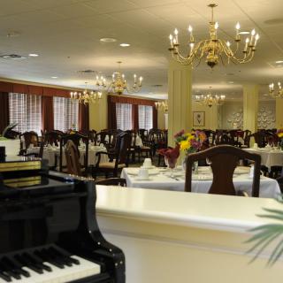 An elegant dining room setting with a black piano and chandeliers.