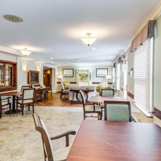 Spacious dining area with neatly arranged tables and chairs, featuring ample natural light from the windows.
