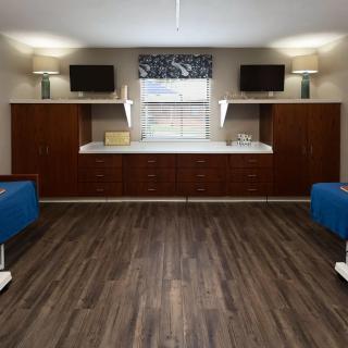 A modern medical examination room with two blue examination tables and wooden cabinetry.