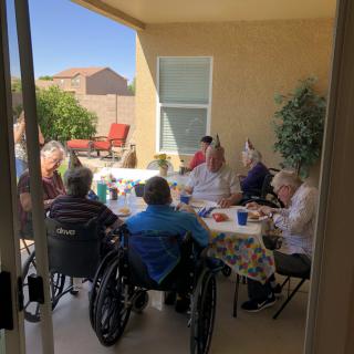 A group of elderly individuals socializing on a sunny patio.
