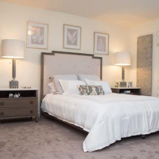 A stylishly decorated bedroom with a large bed, elegant lamps, and matching nightstands.