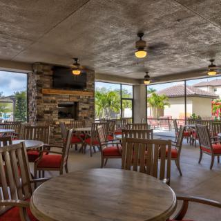 A cozy restaurant interior with wooden tables and chairs, featuring a fireplace and ample natural light from large windows.