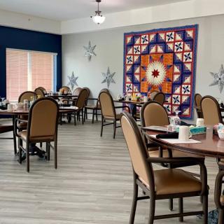 An empty dining room with decorated walls and neatly arranged tables and chairs.