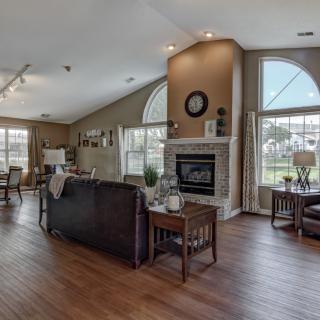 Spacious living room with a fireplace and large windows allowing natural light to illuminate the wood-floored interior.