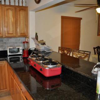 A kitchen with wooden cabinets, a red countertop stove, and a connected dining area.