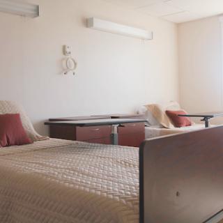 A clean and minimalist hospital room featuring two beds and simple decor.