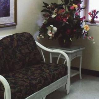 A cozy waiting room with a floral arrangement on a side table next to a patterned sofa.