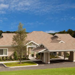 A modern residential building surrounded by lush greenery under a clear blue sky.
