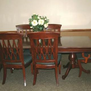 A wooden dining table set with four chairs and a centerpiece of white flowers.
