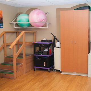 A home exercise room featuring yoga balls, a wooden staircase, and storage cabinets.