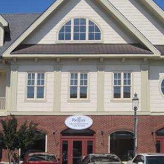 A two-story building with a brick facade and multiple windows, featuring a storefront on the ground floor.