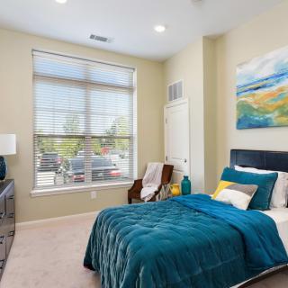 A modern bedroom with teal bedding, large window, and contemporary decor.