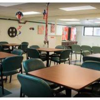 An empty cafeteria with rows of tables and chairs, decorated with hanging ornaments.