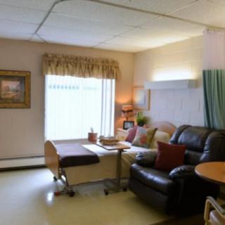 A cozy hospital room with a bed and sofa near a window.
