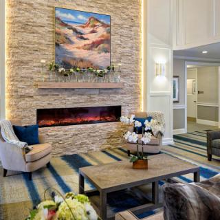 A cozy living room with a stone fireplace, modern decor, and comfortable seating.