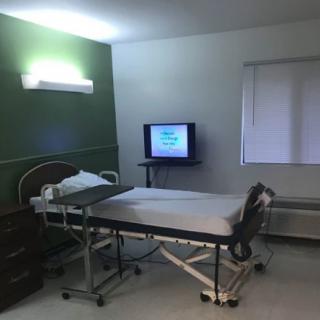 An empty hospital room with a bed and a television.