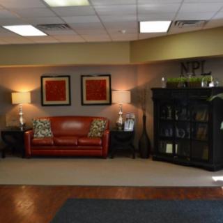 A well-decorated office lobby with a red leather sofa and stylish lighting.