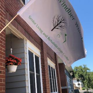 A flag advertising a business, accompanied by a flower pot, against a brick building backdrop.