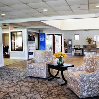 A cozy lobby area featuring patterned chairs and a small table with flowers.