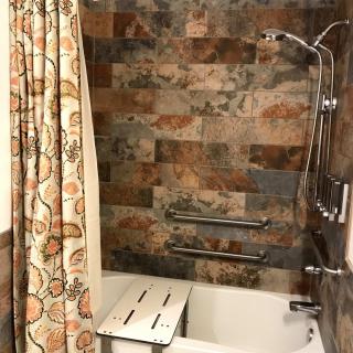 A bathroom featuring a bathtub with tiled walls, a decorative shower curtain, and a shower head.