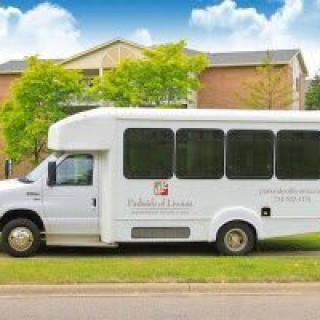 A white shuttle bus parked on a grassy area in front of a building.