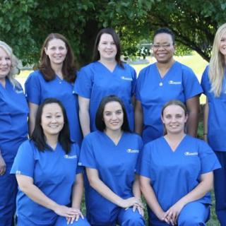A group of medical professionals in blue uniforms posing outdoors.