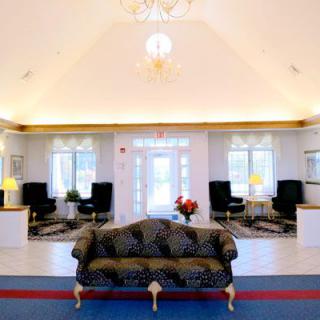 A spacious and elegantly decorated lobby area with a central sofa, complemented by ambient lighting from chandeliers and large windows.