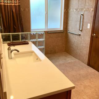 A modern bathroom with a long vanity and open shower area.