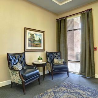 A cozy sitting area with two leather chairs, a small table, and artwork on the wall.